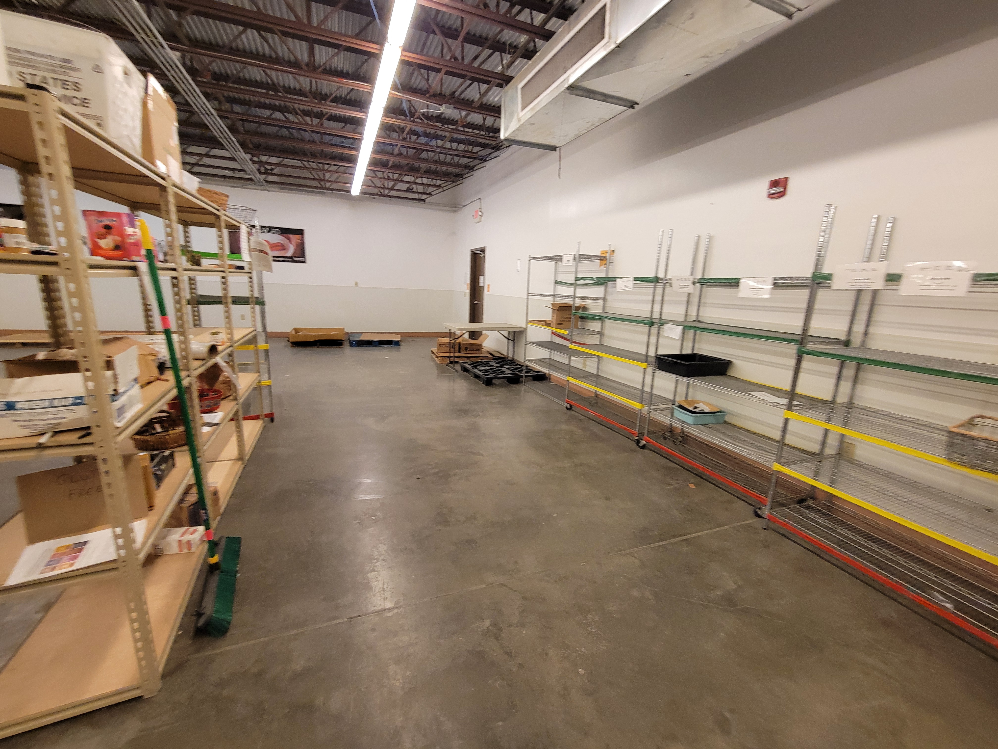 Mostly empty shelves and pallets in a warehouse.
